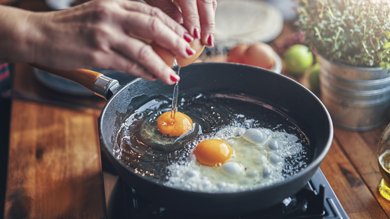 Hands cracking egg into pan