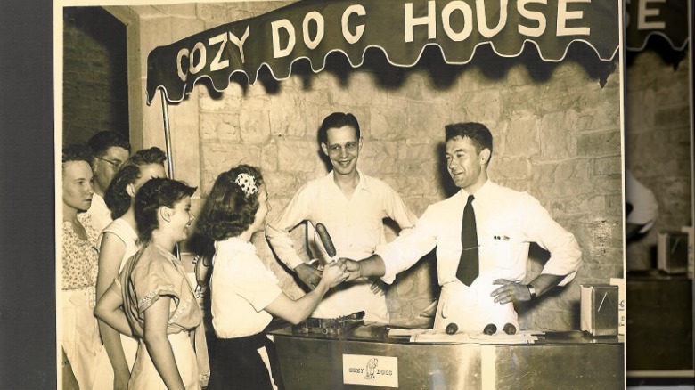 Black and white photo of man serving a Cozy Dog