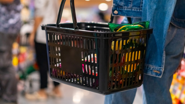 person holding shopping basket in grocery store