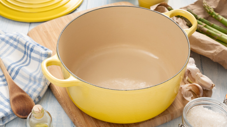 A yellow Dutch oven on wooden cutting board