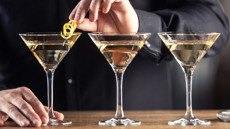 bartender garnishing martini with lemon