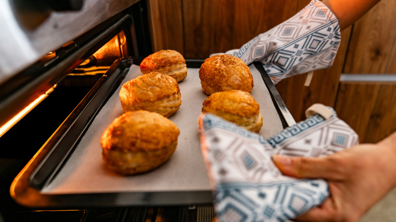 Hand grabbing pastries out of open oven