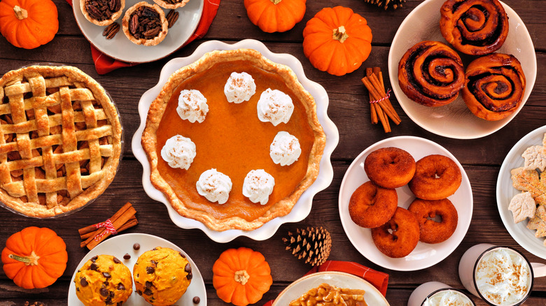 A top-down view of several popular autumn desserts like pumpkin pie, cinnamon rolls, maple donuts, and apple pie.