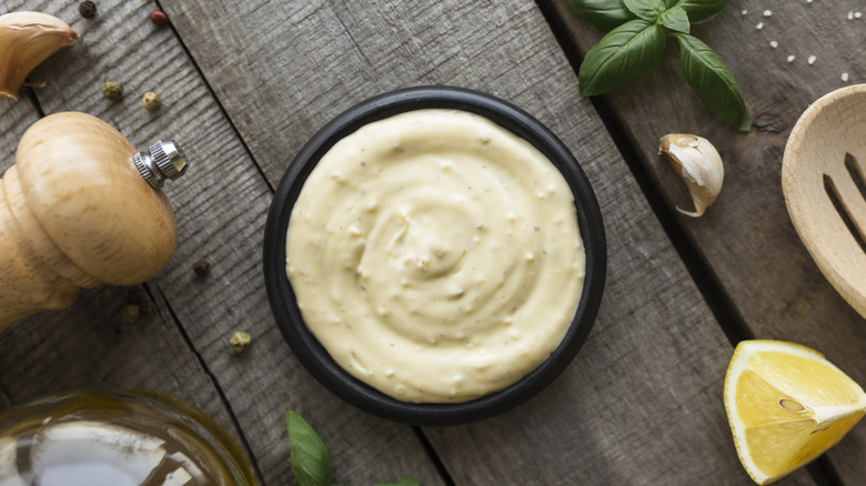Homemade mayo surrounded by herbs 
