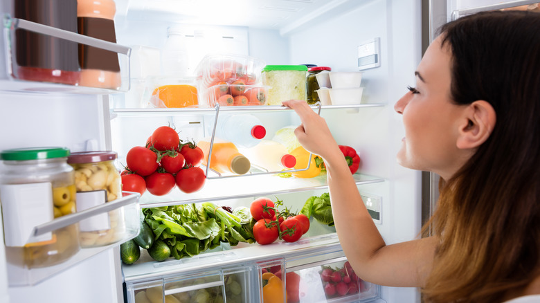 woman searching through fridge