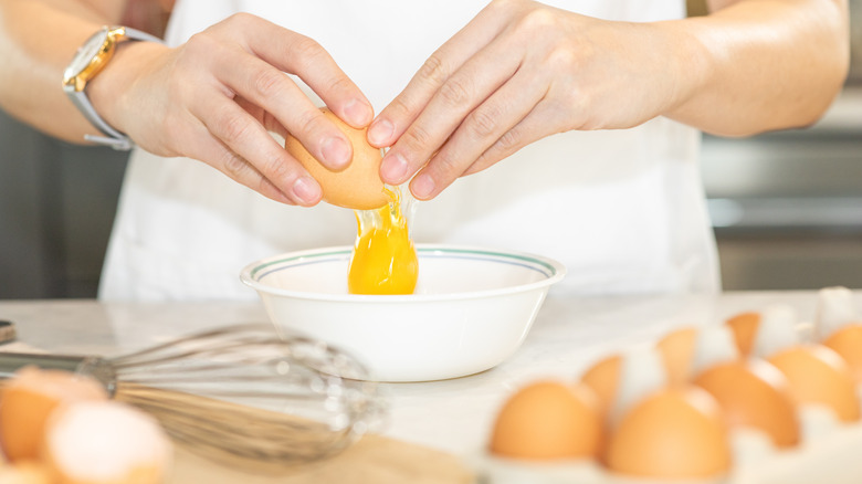 Hands cracking an egg into a bowl