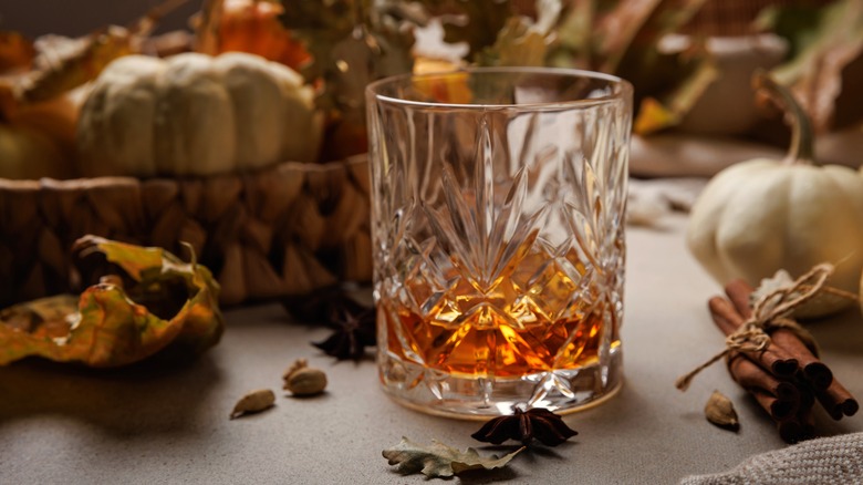 Glass of bourbon with pumpkins and spices