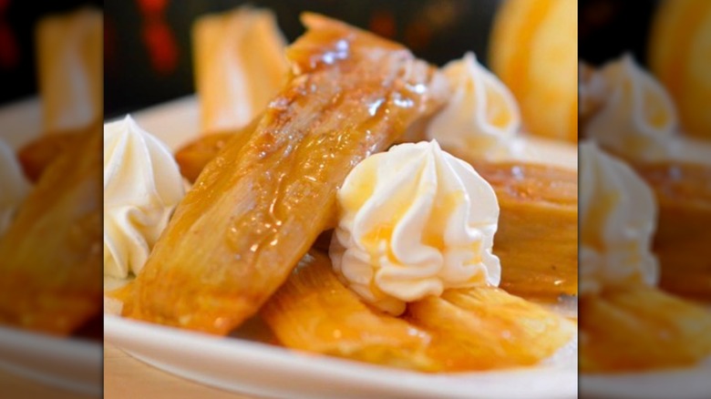 Pumpkin spice tamales piled on plate with dollop of whipped cream