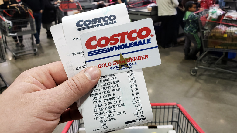 holding a Costco membership card and receipt 