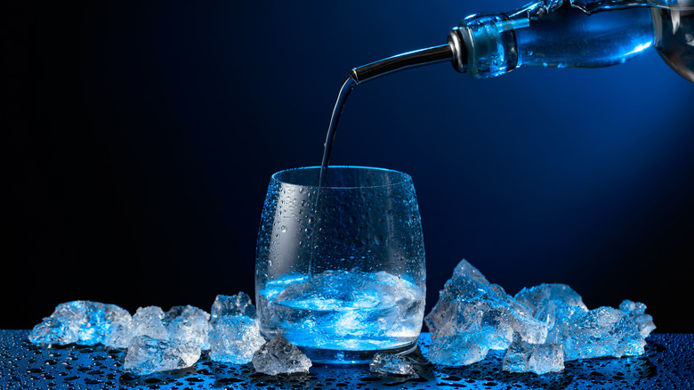 vodka pouring from bottle into glass with ice