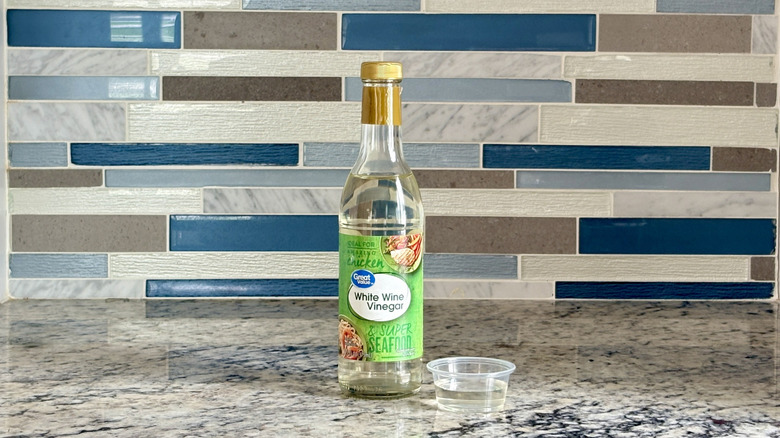 A bottle of Great Value white wine vinegar sits on a countertop.