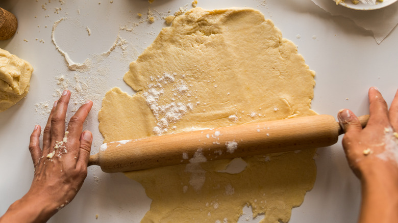hands rolling out dough with rolling pin