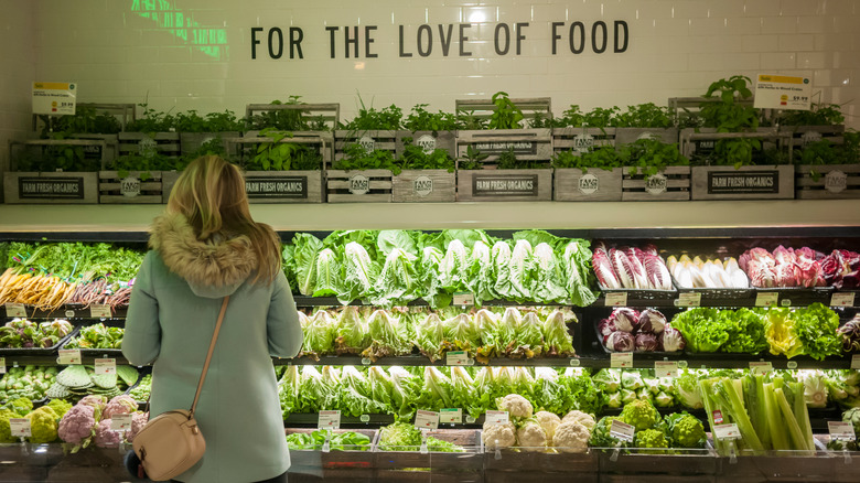 woman standing in front of whole foods produce section