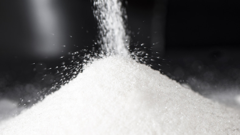 pouring granulating sugar onto pile