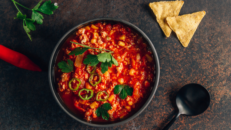 Bowl of meat chili with tortilla chips and spoon