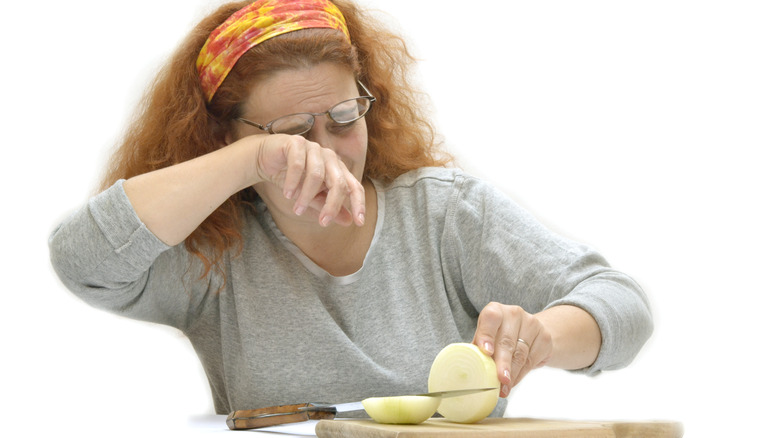 A woman crying while cutting onions 