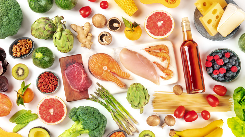 An overhead view of an assortment of grocery items like meats, nuts, cheese, and produce