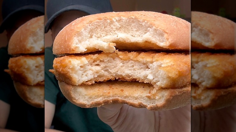 Close-up of someone showing a Dollar Tree chicken sandwich with a bite taken out