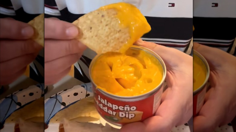 Close-up of hands dipping a chip into a can of jalapeño cheddar dip