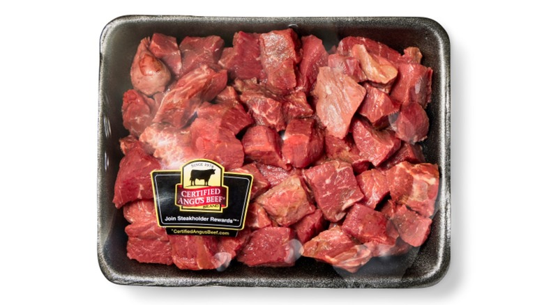 Pre-packaged raw cubed stew meat on a white background