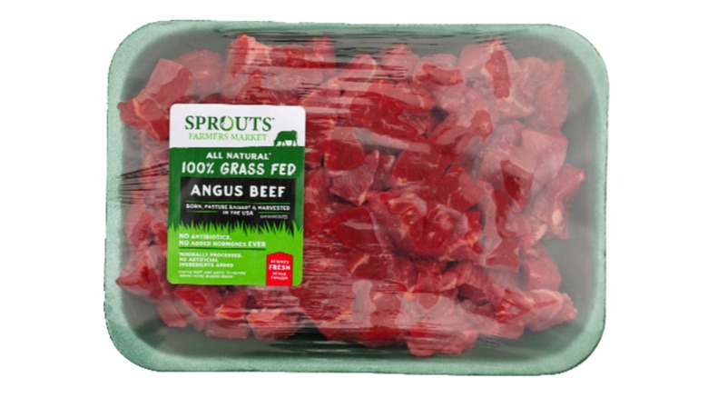 Pre-packaged raw cubed stew meat from Sprouts on a white background