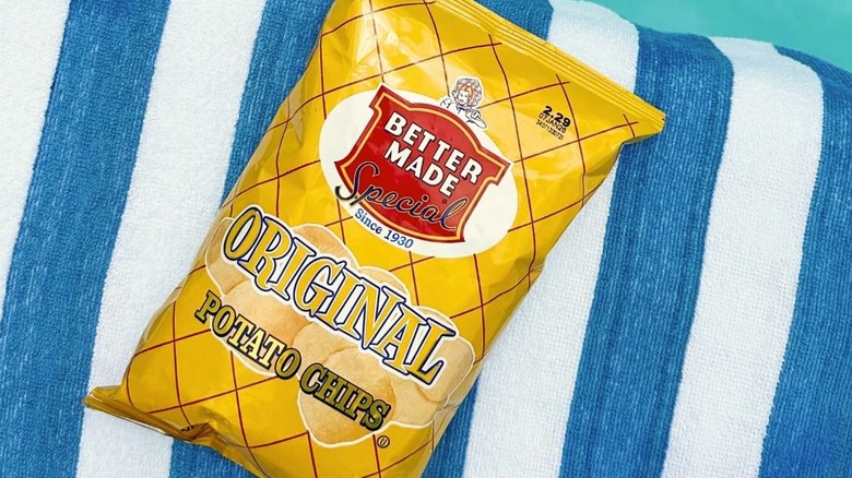 bag of Better Made potato chips on striped towel next to a pool