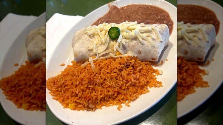 A burrito with rice and refried beans on a plate, served at On The Border