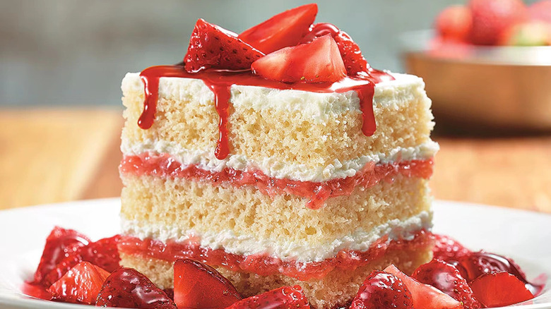 Strawberries & cream shortcake on white plate of strawberries