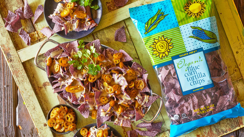 Bag of organic blue corn tortilla chips on a table with scattered nachos
