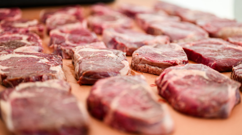 Raw steaks lined up on table