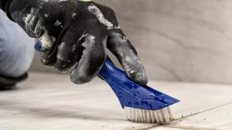 person scrubbing grout with brush