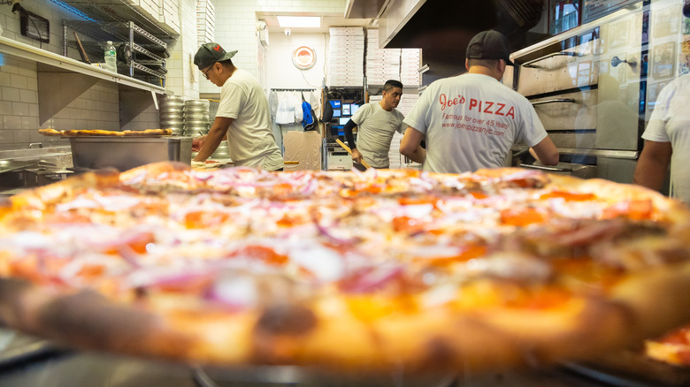 A photo of a pizza and the kitchen of Joe's Pizza in NYC