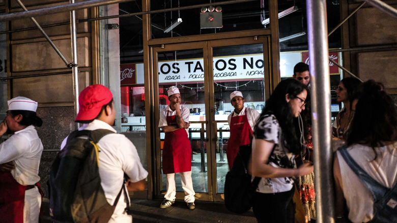 The outside of LOS TACOS No. 1 in New York City with people and workers standing outside