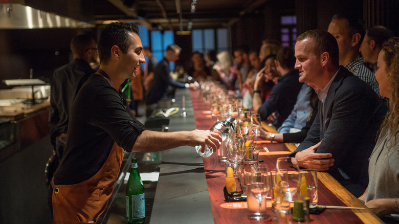 A bartender pours a glass at a dinner prepared by Masayoshi Takayama