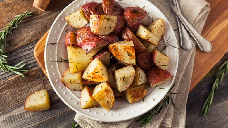 roast potatoes on plate on wood table with rosemary