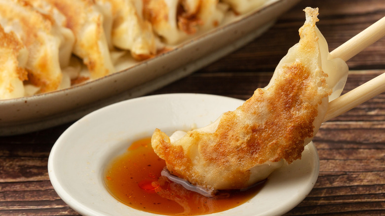 Crispy-bottom dumpling in sauce with chopsticks