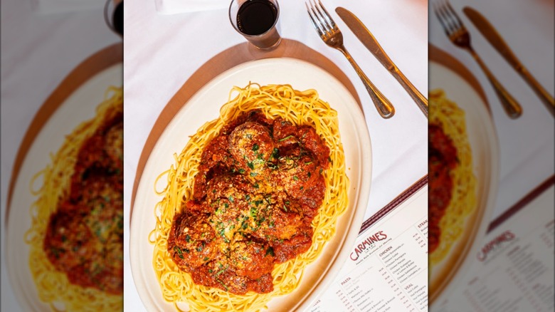 Carmine's signature meatballs and spaghetti next to a menu on a white tablecloth