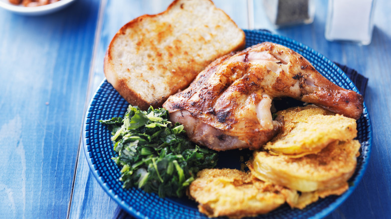 A plate of smoked chicken with collard greens and fried green tomatoes