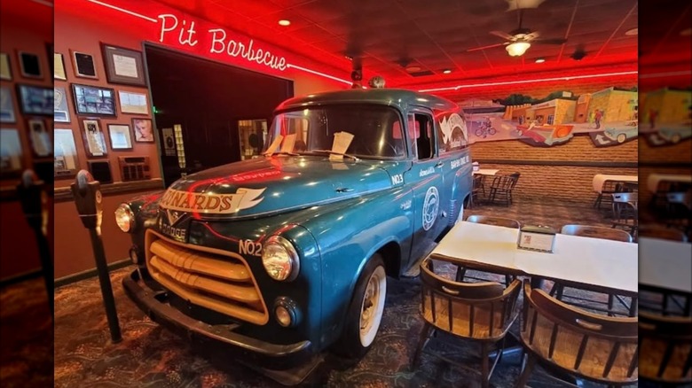 The interior of Leonard's Pit Barbecue, with a vintage car in the middle of its dining room