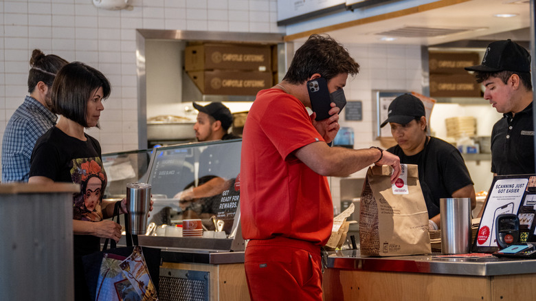 A person picking up their order from the cash register at Chipotle
