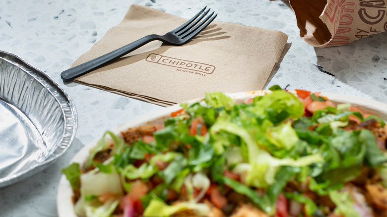 Chipotle food on plate with fork and napkin with word chipotle on it