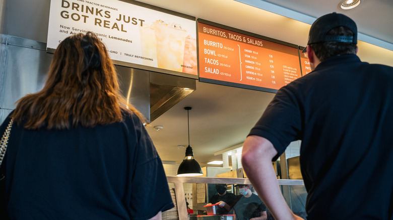 Two people looking at the menu at Chipotle and deciding what they'd like