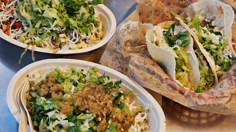 Two bowls and one portion of soft tacos from Chipotle on a table