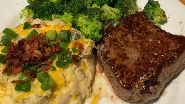 Chili's steak, broccoli, and cheesy mashed potatoes with bacon on a white plate