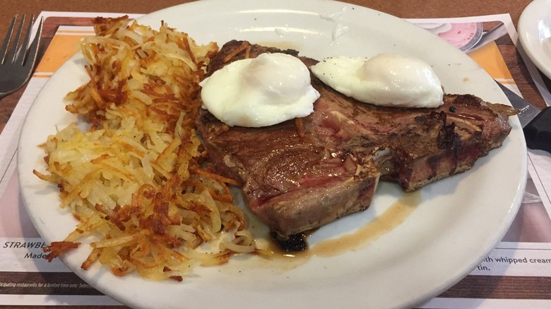 Steak, overeasy eggs, and hashbrowns on a white plate at Denny's
