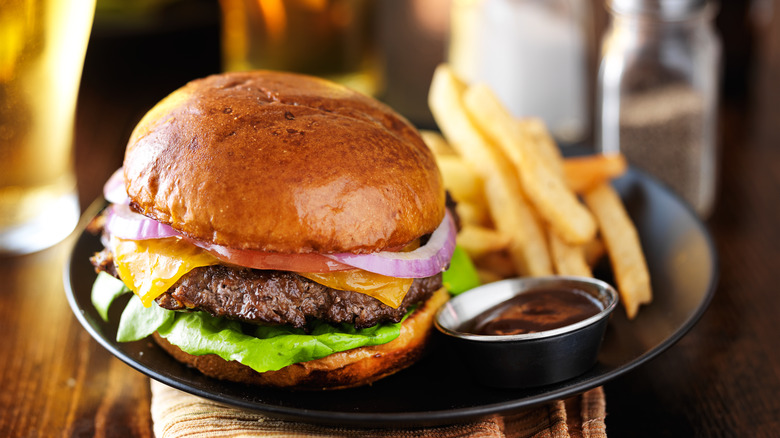 Cheeseburger and fries on plate served with beer at restaurant