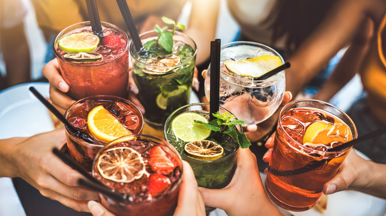 Hands holding various cocktails in a toast