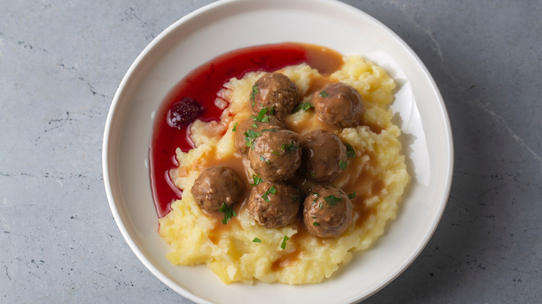 Traditional Swedish meatballs on a white plate with mashed potatoes and lingonberry jam