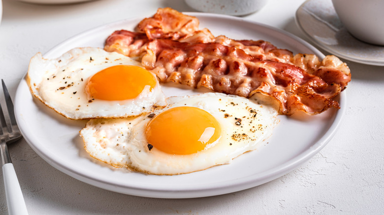 breakfast with perfectly fried eggs and bacon on a sunny table