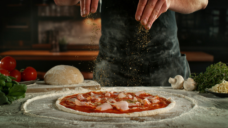Chef making fresh pizza on a table covered in dough